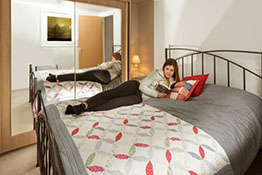 Woman reading on bed in container housing unit bedroom