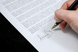 Hand with a pen signing a document