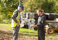 Two men in a field. One in a hi vis jacket