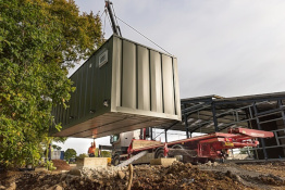 Container home unit being lowered by a crane on a flat bed truck