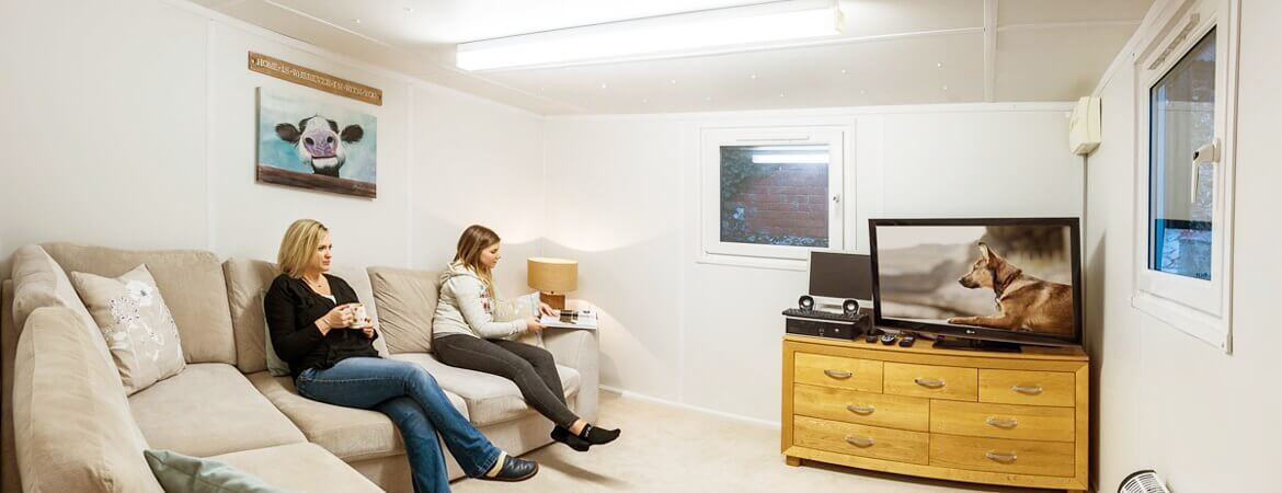 Two women watching television in container home lounge